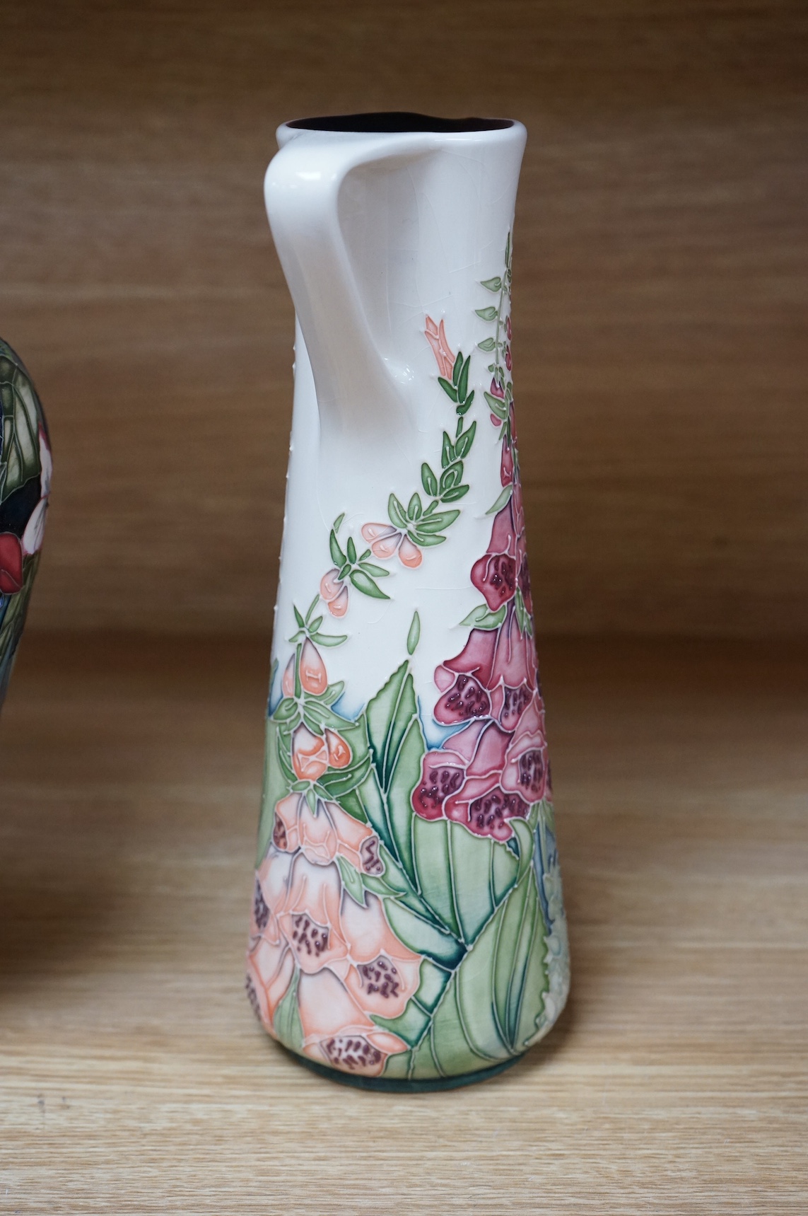 A Moorcroft ‘Nostalgia’ pattern vase together with a similar ‘Foxglove’ pattern ewer, 24.5cm. Condition - good, some crazing